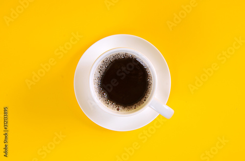 Black coffee in a coffee cup top view isolated on yellow background