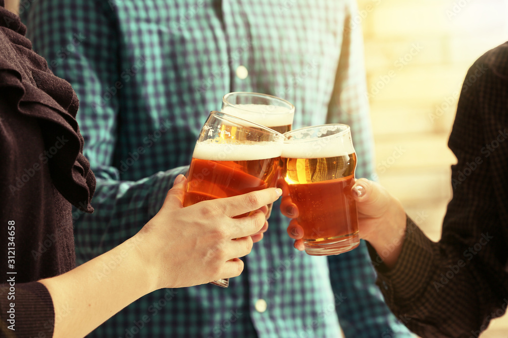 People clinking glasses of beer indoors People clinking glasses of beer indoors