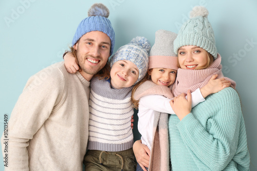 Happy family in winter clothes on color background photo