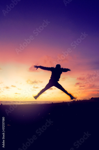 Silhouette of man jumping on beach at sunset