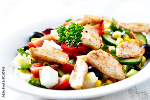 Healthy Salad with Chicken Briest, Feta Cheese, Blcak Olives, Cucumber, Red Pepper and Sweet Corn. Bright wooden background.