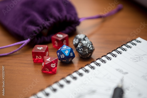 Set of pen, notebook, and dices to play role game like dungeons and dragons. Purple bag to storage the dices.