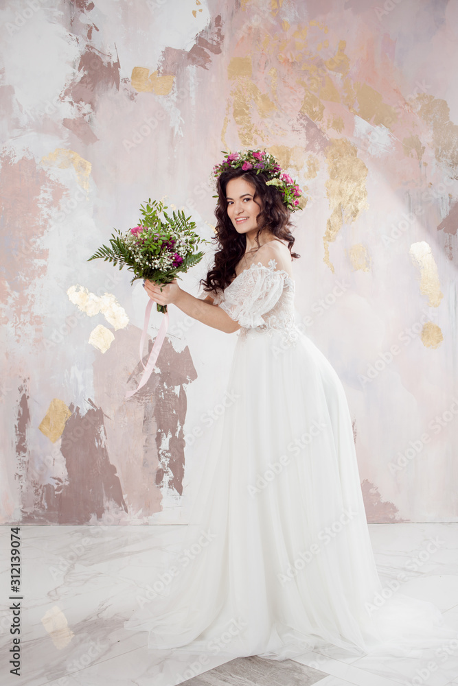 Elegant brunette girl bride with flowers. Beautiful young bride in a lush wedding wreath of fresh flowers