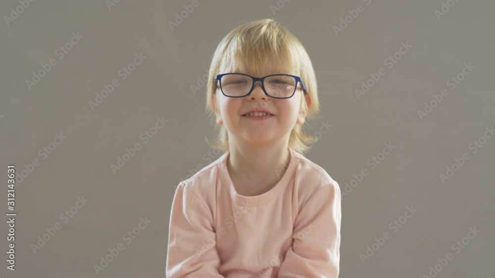 Portrait of funny blond child in new glasses. Boy puts on and adjusts glasses Portrait of funny blond child in new glasses. Boy puts on and adjusts glasses