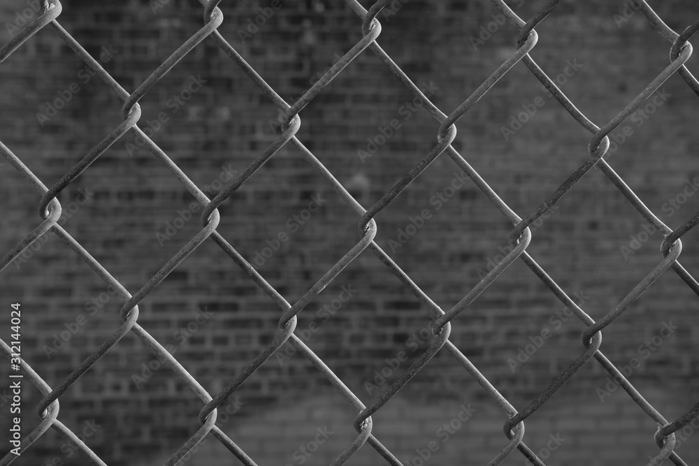 Fototapeta premium black and white closeup of chainlink fence with grunge urban background