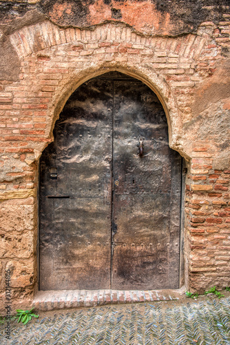 A very old moorish antique steel doorway with a brick wall