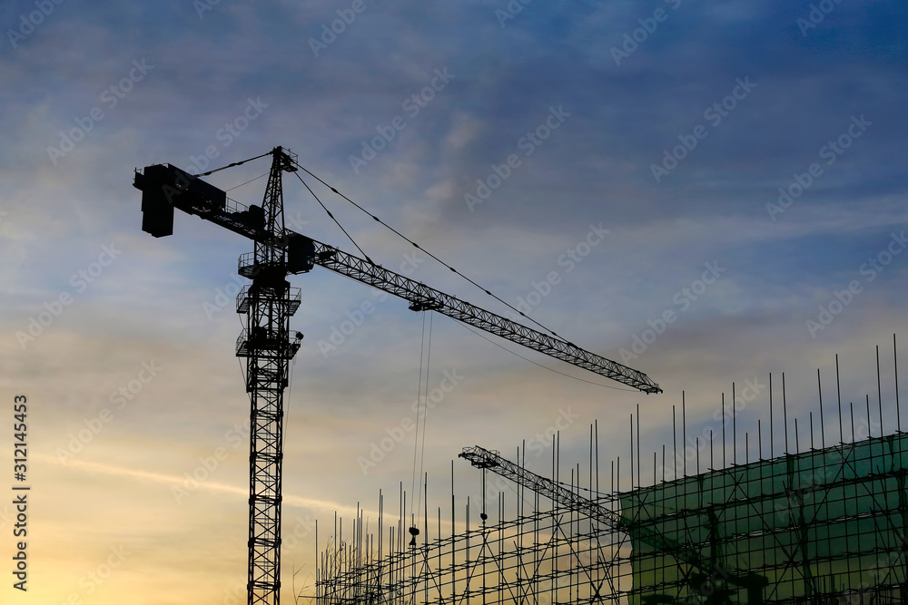 Cranes at construction sites, silhouetted at sunrise