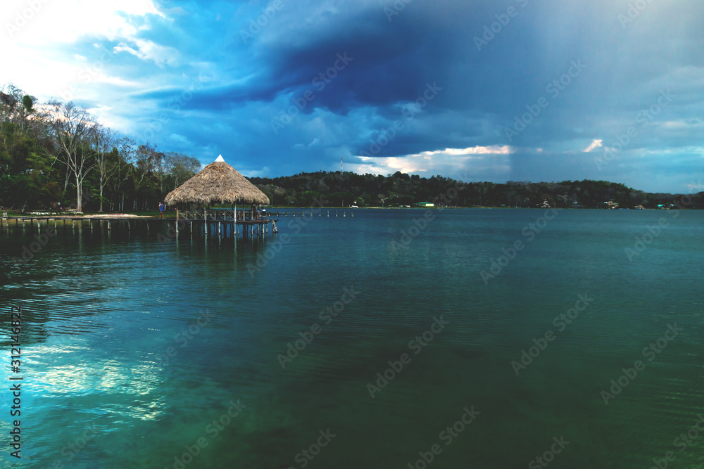 Wooden old dock during sunset with massive raincloud at lake Itza, El Remate, Peten, Guatemala