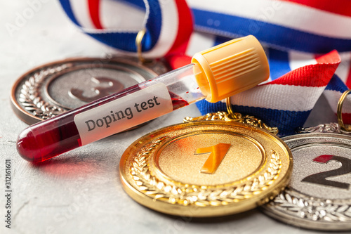 Doping test. Gold, silver and bronze medal and test tube with blood on a gray background