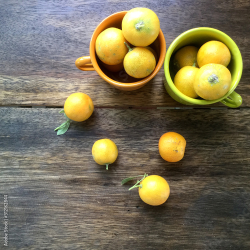  fresh mini orange fruits with leaves, orange pile laying on the wooden table 