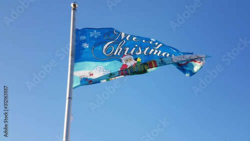 Merry Christmas flag flying in the breeze against blue sky on Xmas Day in Lutterworth UK photo