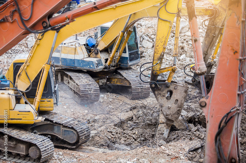 Many jackhammer on an excavator are demolishing building structures. dismantling of a house. photo