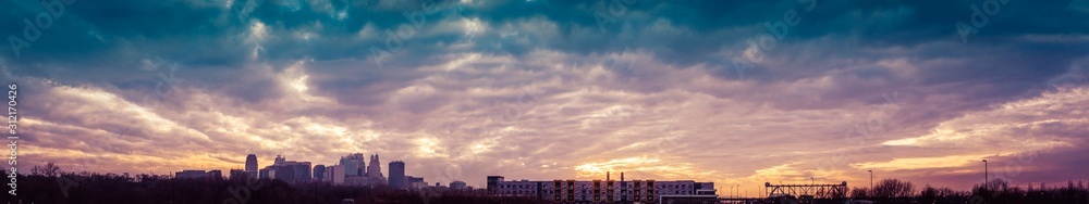 Panorama of Kansas City skyline and rail bridge under vivid sunset