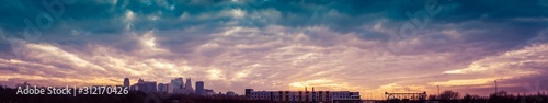 Panorama of Kansas City skyline and rail bridge under vivid sunset