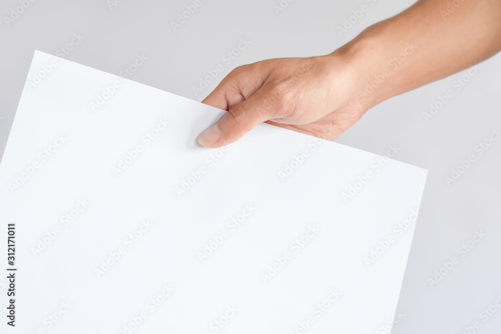 hand holding blank sheet of white paper isolated on gray with copy space for text and picture hand holding blank sheet of white paper isolated on gray with copy space for text and picture