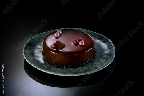 Torta ai 3 cioccolati con piatto su piano nero lucido