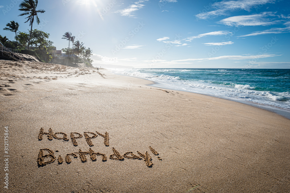 Happy Birthday written in the sand on Sunset Beach in Hawaii with palm