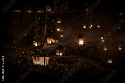 A lantern illuminated in the woods with several lanterns behind it