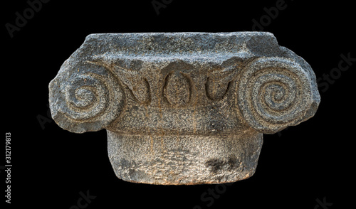 ancient greek ionic style basalt stone capital from the katzrin open air museum in the golan heights in israel isolated on a black background photo