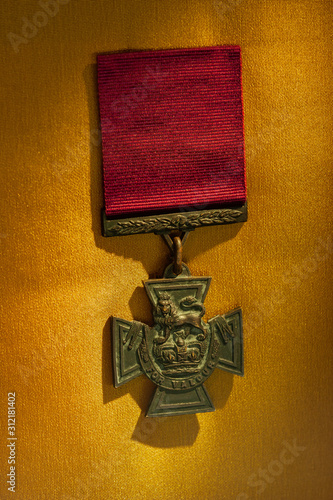 Leinwand Poster Close up shot of Victoria Cross medal on golden background