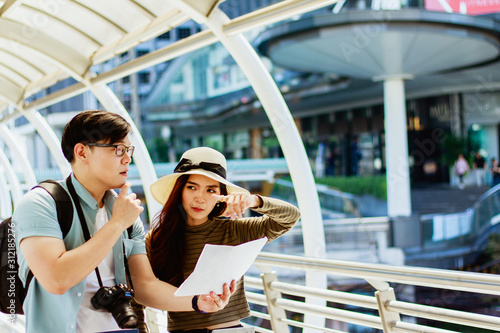 Portrait of young Asian male and female tourists Viewing map of tourist attractions And consult about travel. The traveling couples concept