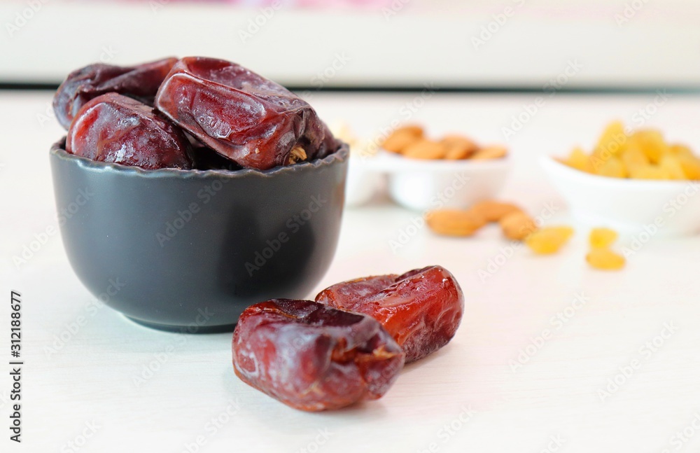 An assortment of healthy nuts in a bowl : almond, cashew, raisins and dates, making a healthy snack alternative