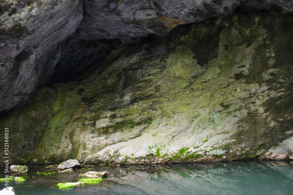 An underground beautiful cave lake with clear water. Volcanically formed cave in which the river is located. Cave healing river with reflection of rocks. Russia, Bashkortostan.