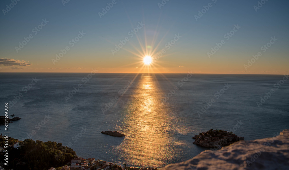 Golden sunrise sunset over the Adratic sea in Montenegro, view from the top of the mountain above St. Stephen island.Quiet place. Relaxing scene.Calm sea water. Beautiful colors in the sky.