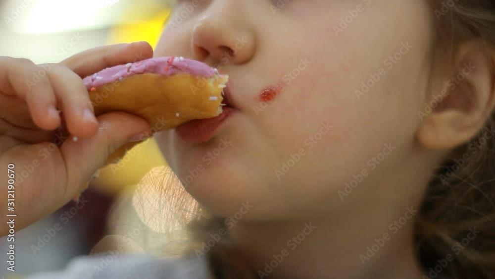 Child eats donut. Closeup baby girl eating doughnut with glase. Delicious, sweet, sweettooth.