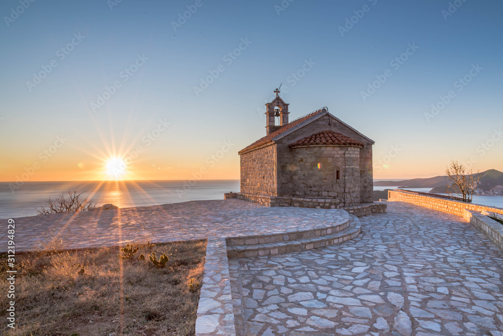 Sunset over the Adratic sea in Montenegro, Serbian Orthodox Church Sveti Sava. view from the top of the mountain above St. Stephen island.Quiet place.
