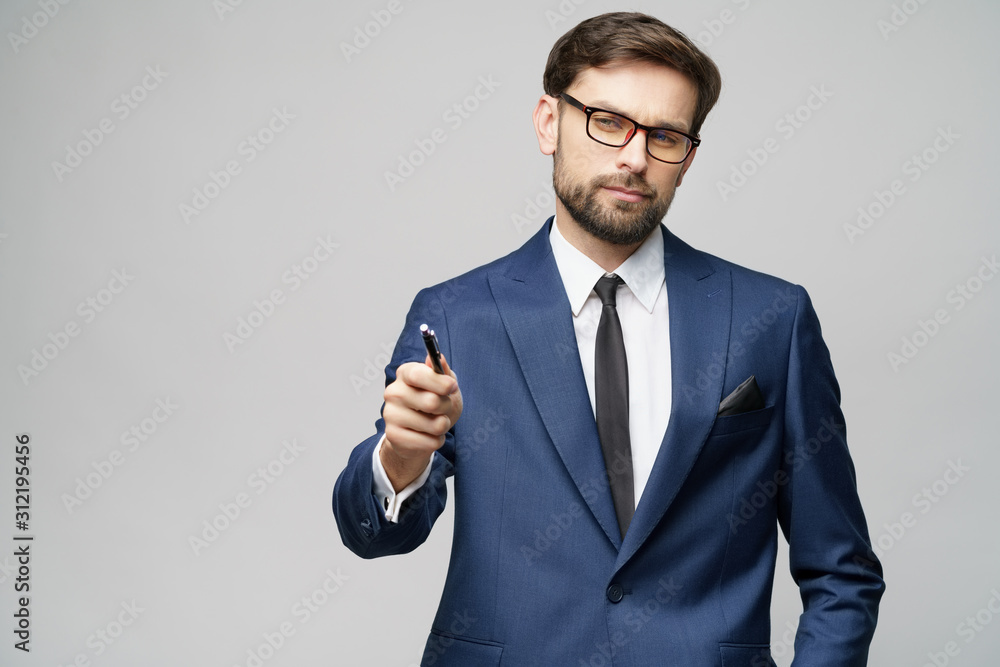 Portrait of a businessman showing pen or pencil at camera over gray background Portrait of a businessman showing pen or pencil at camera over gray background