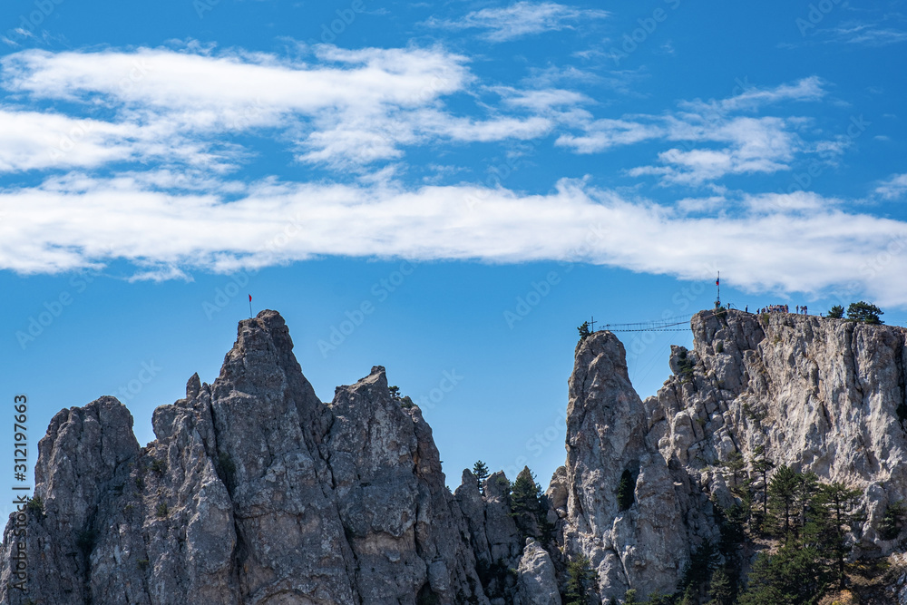 Sharp Ai-Petri cliffs with suspension bridge against a blue sky.