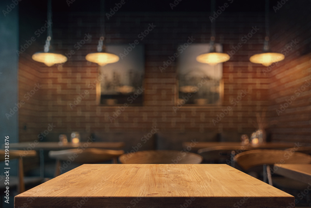 Empty tabletop in the coffe shop at night over defocused background with copy space - obrazy, fototapety, plakaty 
