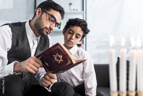 Obraz na plátně handsome jewish father and son reading tanakh in apartment