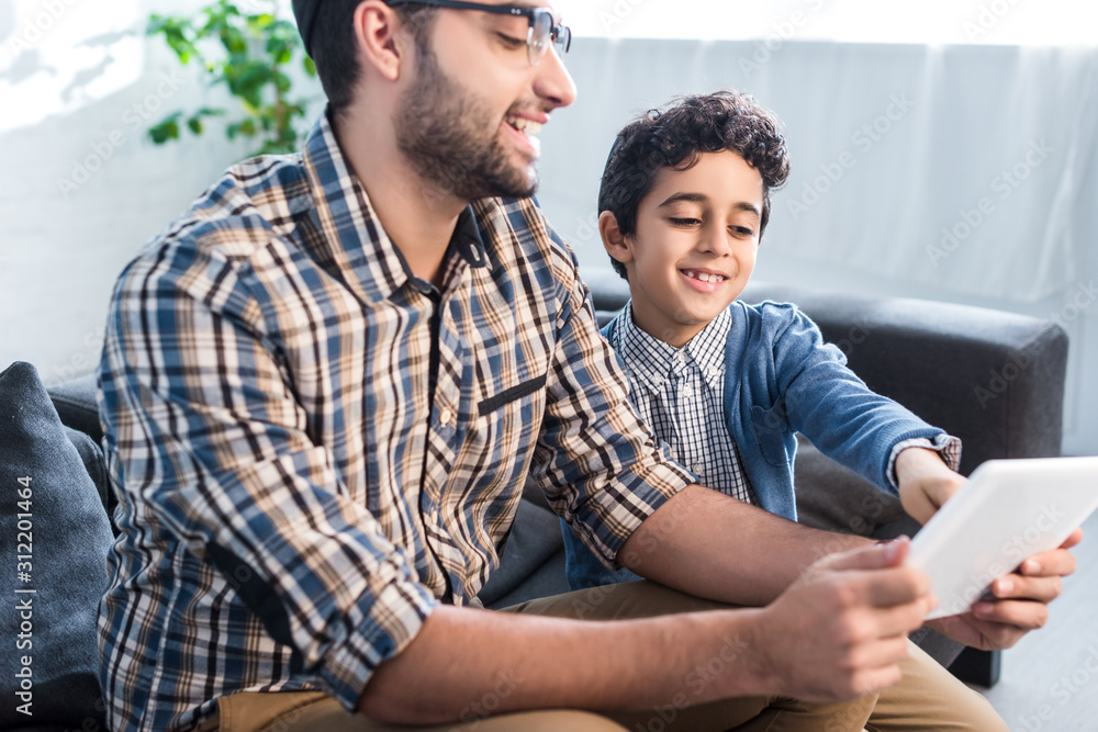 smiling jewish father and son using digital tablet in apartment smiling jewish father and son using digital tablet in apartment