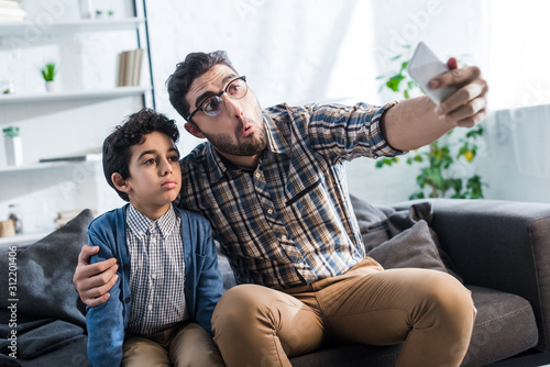  jewish father taking selfie with cute son in apartment