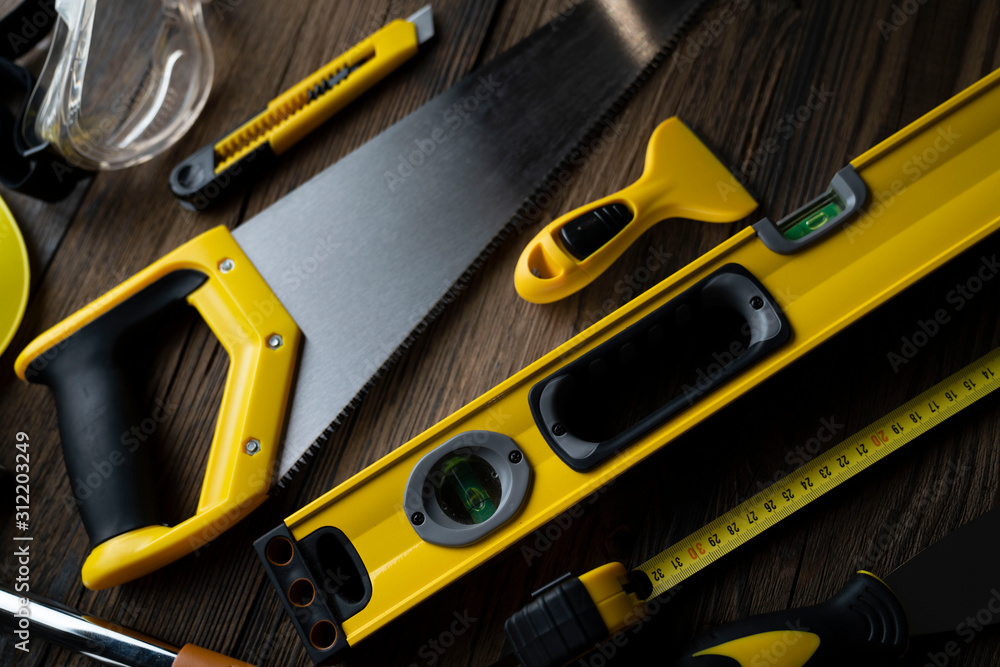 Contractor concept. Yellow hardhat, libella and other tools on the rustic wooden background. Contractor concept. Yellow hardhat, libella and other tools on the rustic wooden background.
