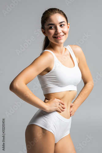 Young beautiful woman body on gray background in white sport clothes © F8  \ Suport Ukraine