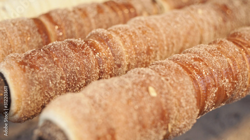 Preparing of Trdelnik - traditional czech bakery. Czech sweet pastry called Trdlo. Trdelnik baking on the street market in Prague. Close up.