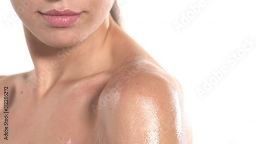 Close-up of woman applying moisturizer cream on shoulder. Girl gently touching her silky skin. Cosmetic product usage