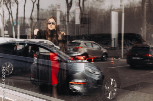 A young woman is choosing a new car in car store