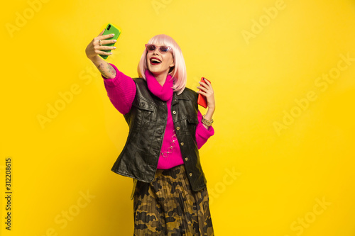It's hard to be influencer. Selfie only in special clothes and make up. Caucasian woman's portrait on yellow background. Beautiful blonde model. Concept of human emotions, facial expression, sales, ad