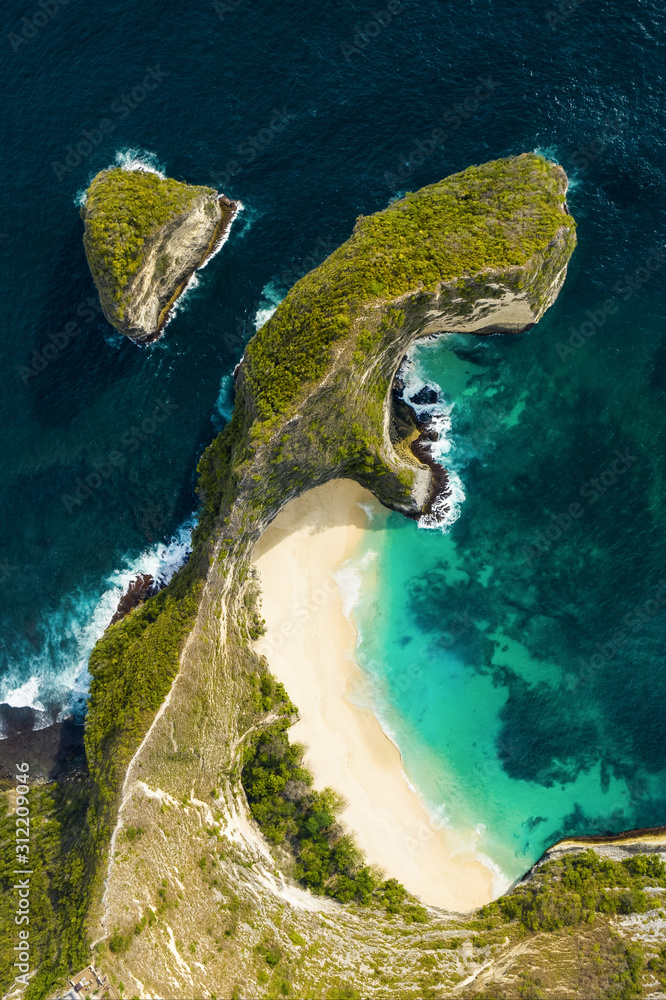 View from above, stunning aerial view of a T-Rex shaped cliffs with the beautiful Kelingking Beach bathed by a turquoise sea. Nusa Penida, Indonesia.