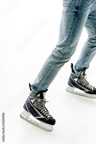 cropped view of man in jeans and skates skating on rink