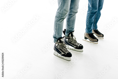 cropped view of young couple in skates skating on rink