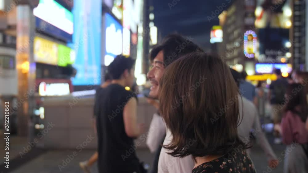 Excited couple walking crazy nightlife Neon streets of Osaka traveling in Asia Excited couple walking crazy nightlife Neon streets of Osaka traveling in Asia