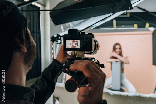 Foto Over shoulder view of videographer filming beautiful model in photo studio