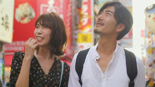 Fun classy Japanese couple explore Osaka food street bright lights background sense expereience