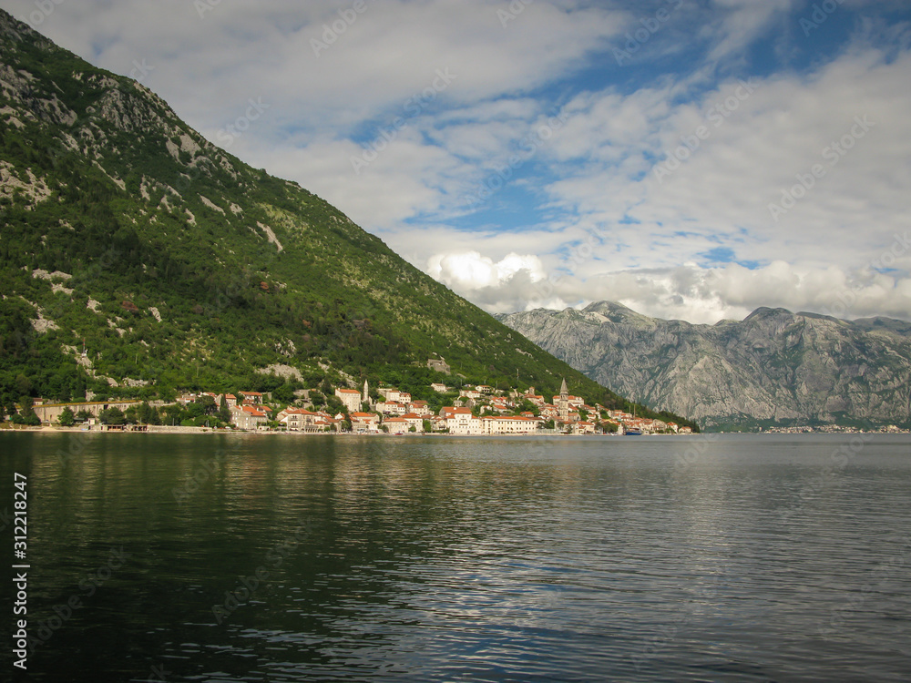 panoramic view from the ship to Perast, Kotor bay and the surrounding mountains, blue sky with white clouds, Montenegro