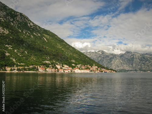 panoramic view from the ship to Perast, Kotor bay and the surrounding mountains, blue sky with white clouds, Montenegro